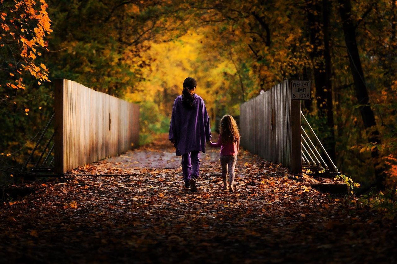 A parent and child walking an autumn trail